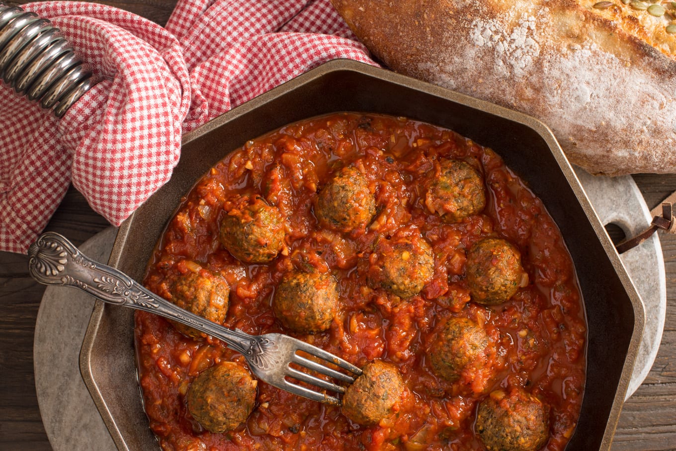 Italian style lentil meatballs with marinara sauce in pan next to loaf of bread