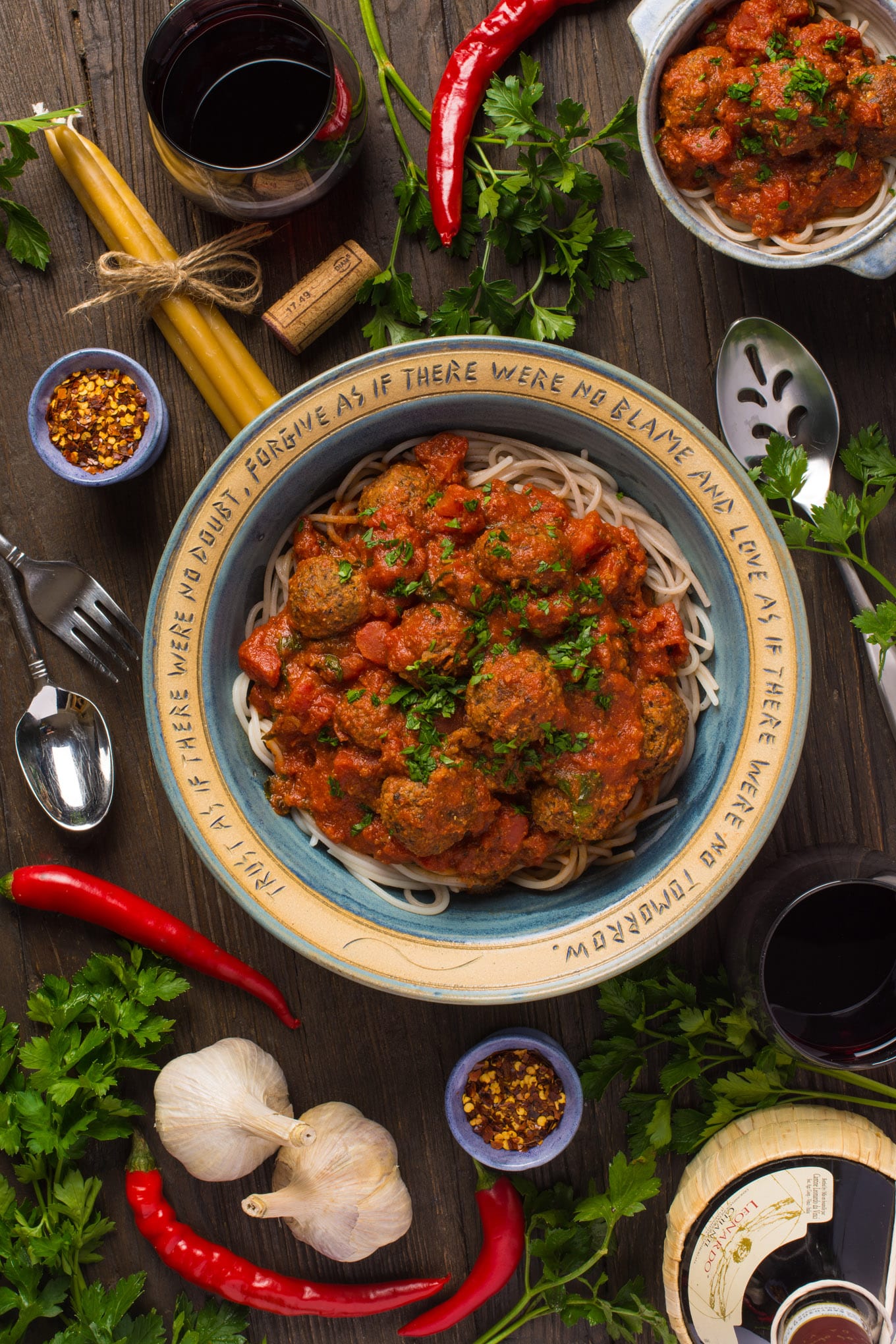 Italian Style Lentil meatballs in marinara sauce in bowls next to wine and fresh vegetables