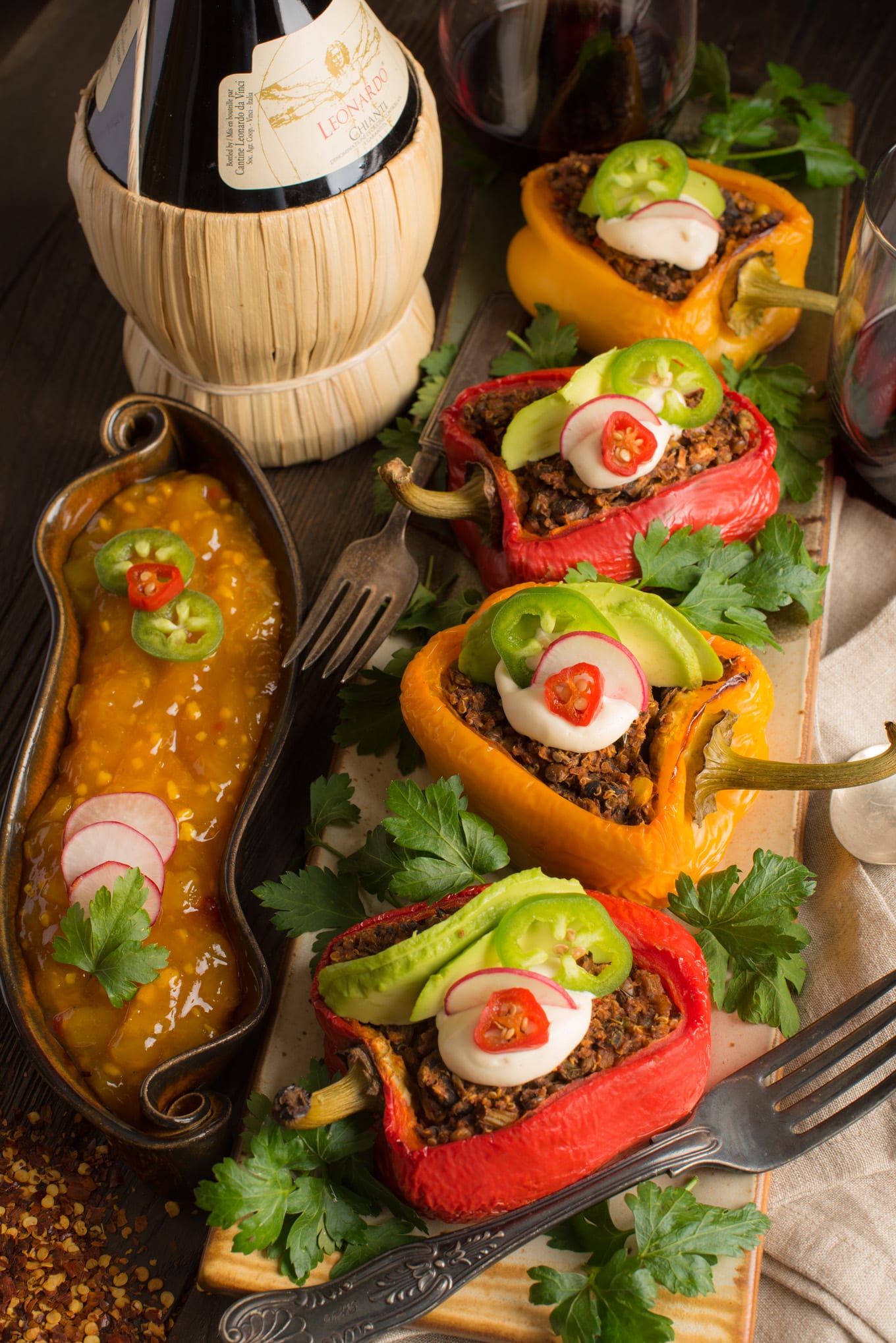 mexican-inspired stuffed peppers on tray with chutney and bottle of wine