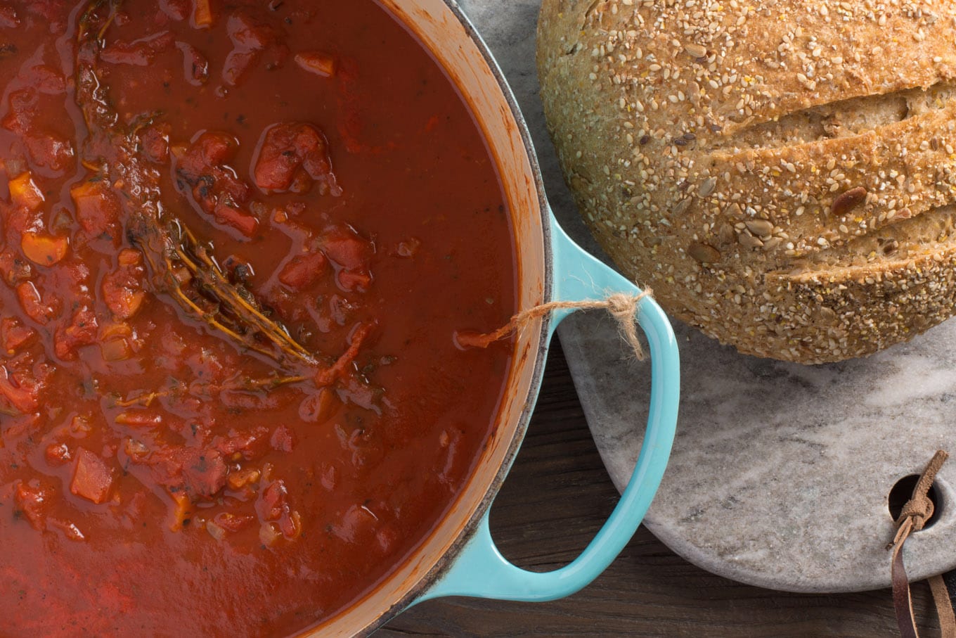 soup in cast iron pot next to loaf of bread