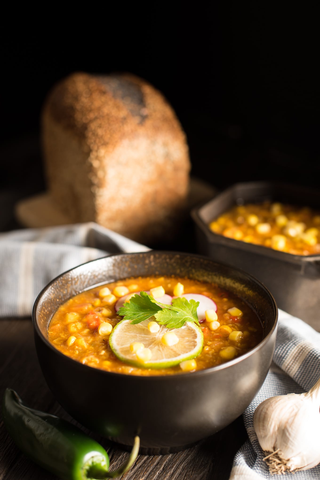 creamy corn chowder in bowl and pot with loaf of bread in background