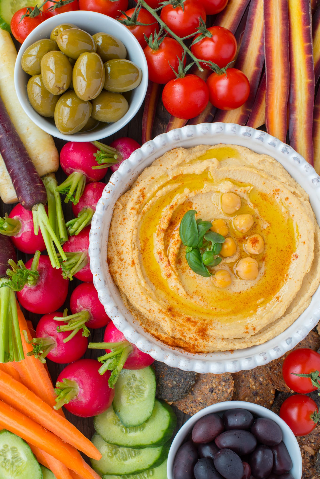 roasted garlic hummus in bowl surrounded by fresh vegetables