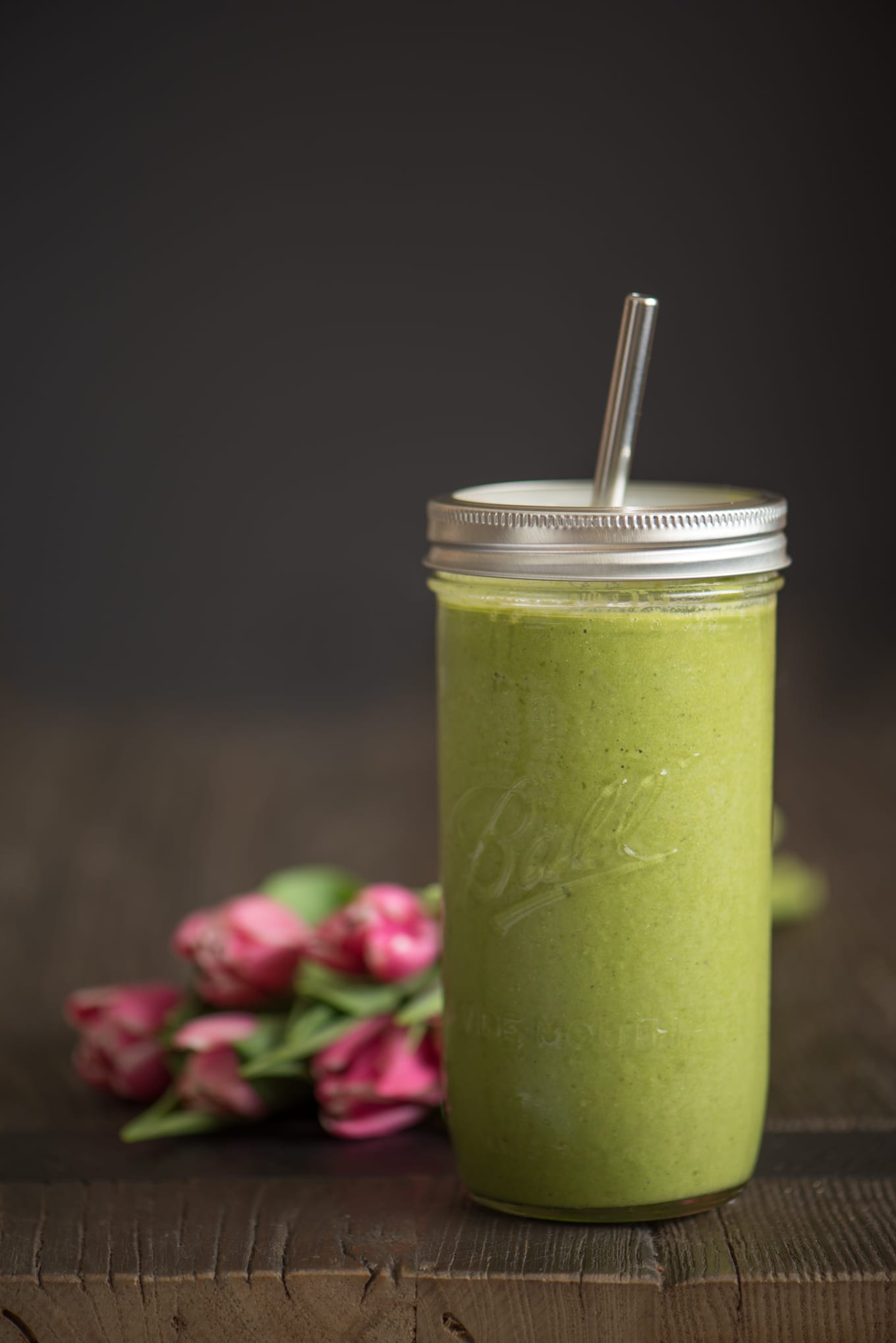super greens smoothie in preserving jar next to pink tulips