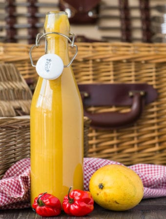 tangy mango lime hot sauce in bottle with picnic basket in background