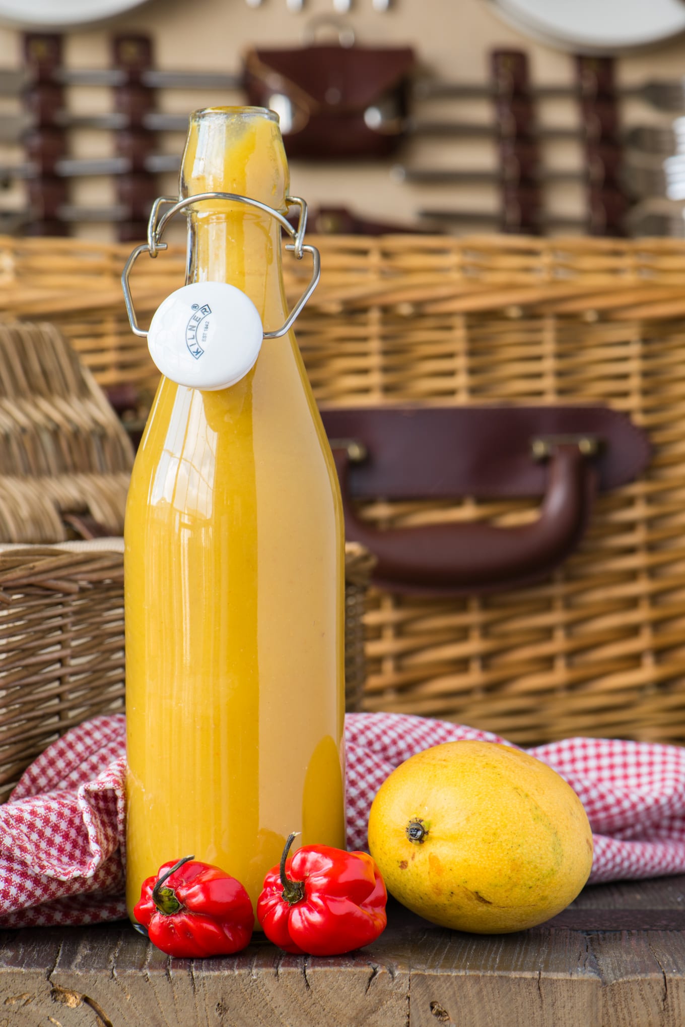 tangy mango lime hot sauce in bottle with picnic basket in background