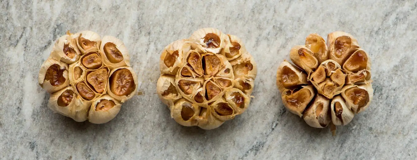 3 heads of roasted garlic on marble slab