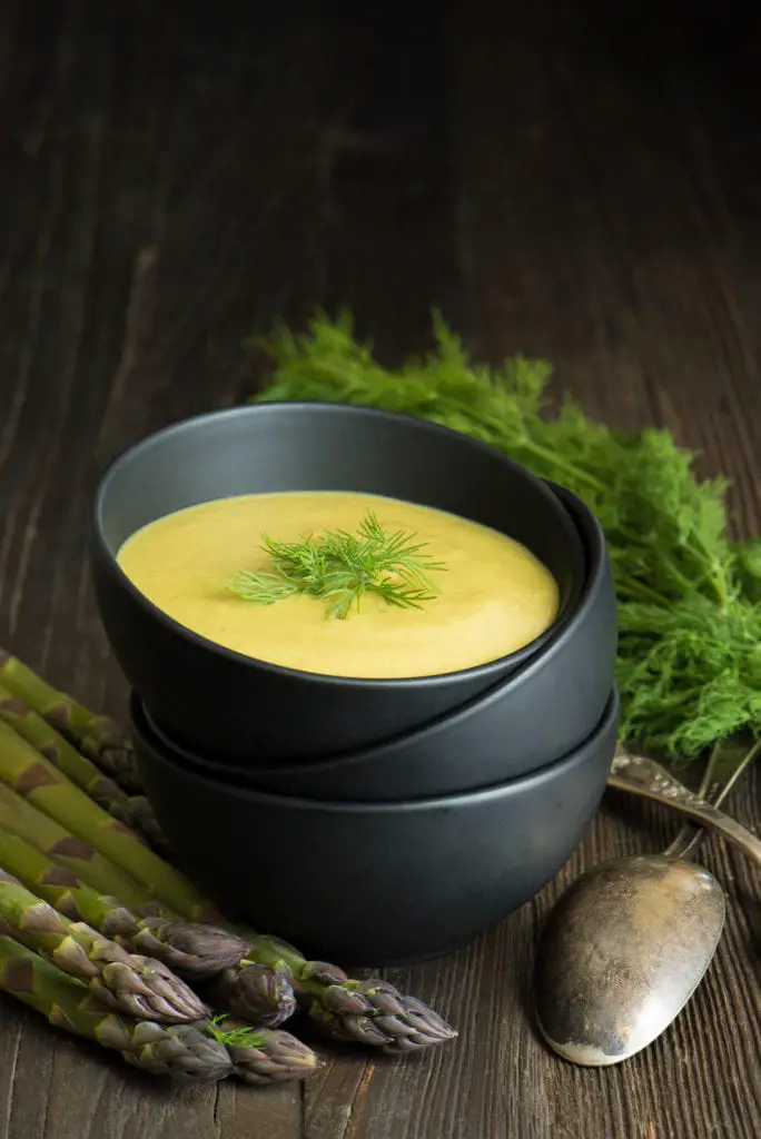 spring detox soup in bowl next to asparagus and fresh dill