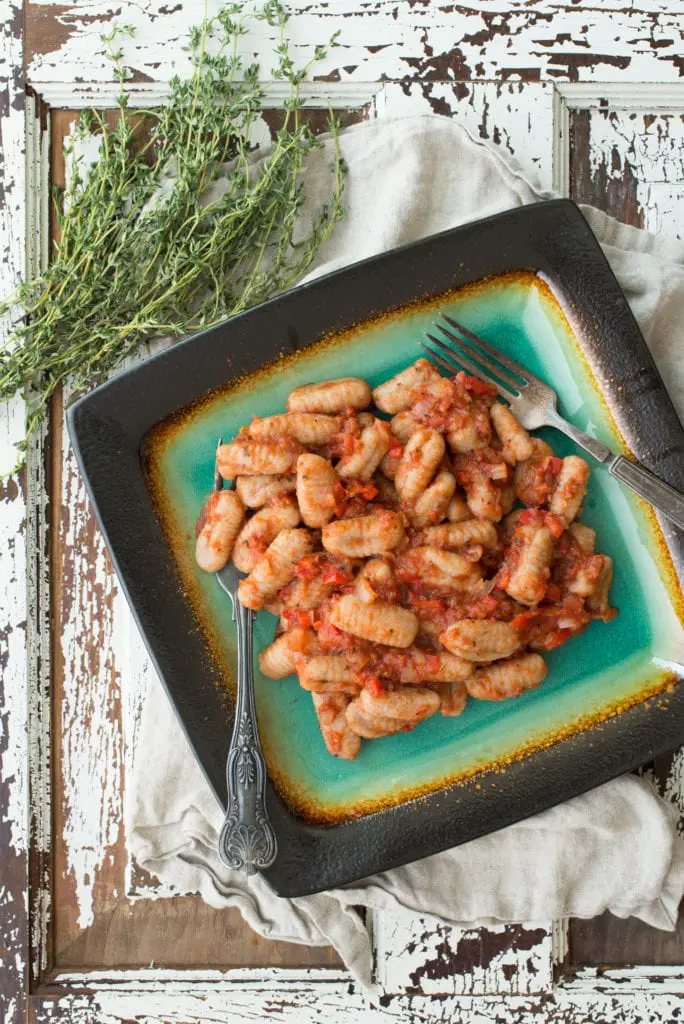 tender vegan gnocchi on plate next to springs of thyme