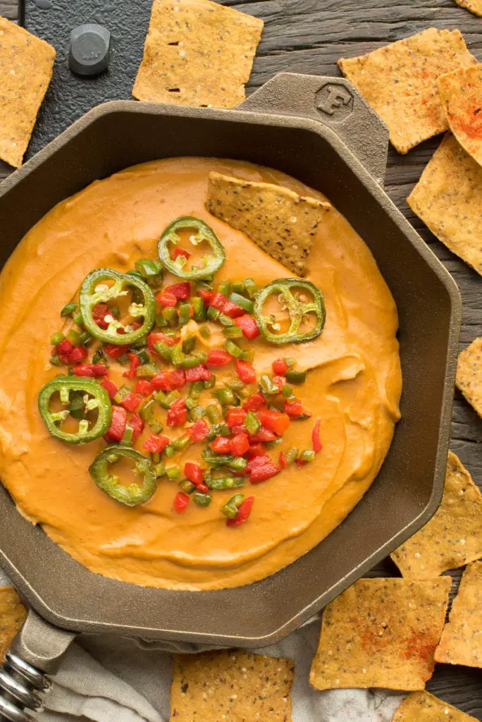vegan cashew queso dip in cast iron pan surrounded by tortilla chips