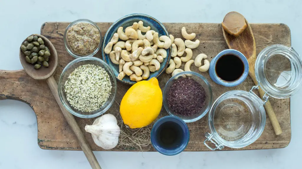 oil free caesar salad dressing ingredients in bowls and spoons on cutting board