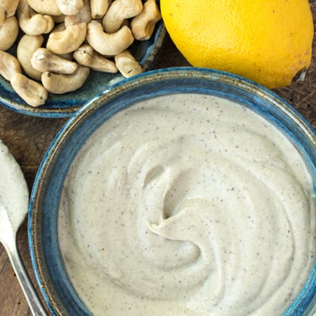 oil free caesar salad dressing in bowl next to cashews and lemon