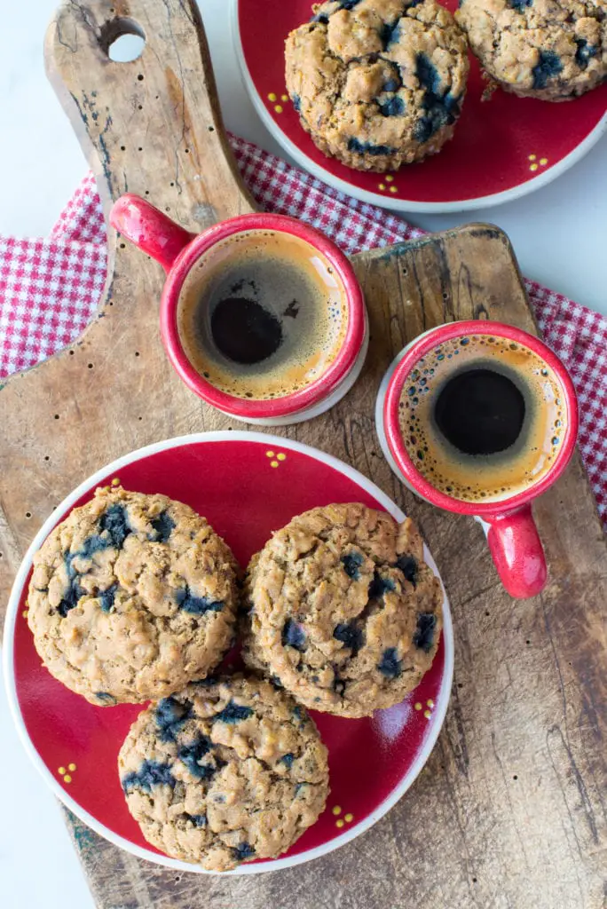 blueberry oatmeal muffins on plate next to coffee in cups