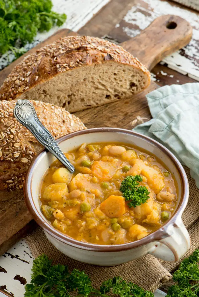 autumn vegetable stew in bowl next to sourdough loaf