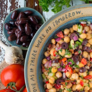 greek chickpea salad in bowl next to olives and tomatoes