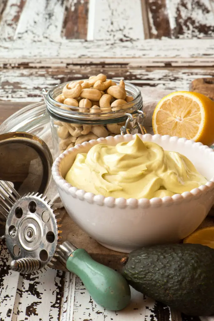 spicy cashew avocado may in bowl next to ingredients and hand mixer