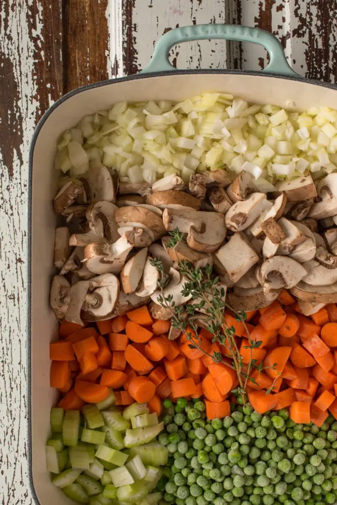 uncooked diced vegetables in cast iron roasting pan