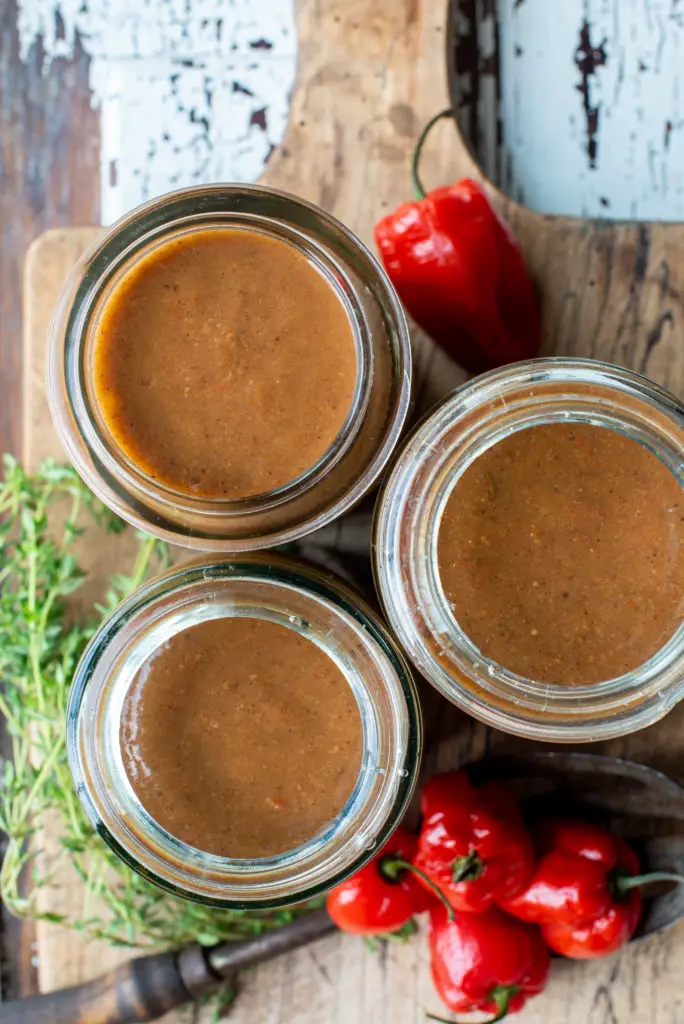 jerk style peach hot sauce in three jars on cutting board