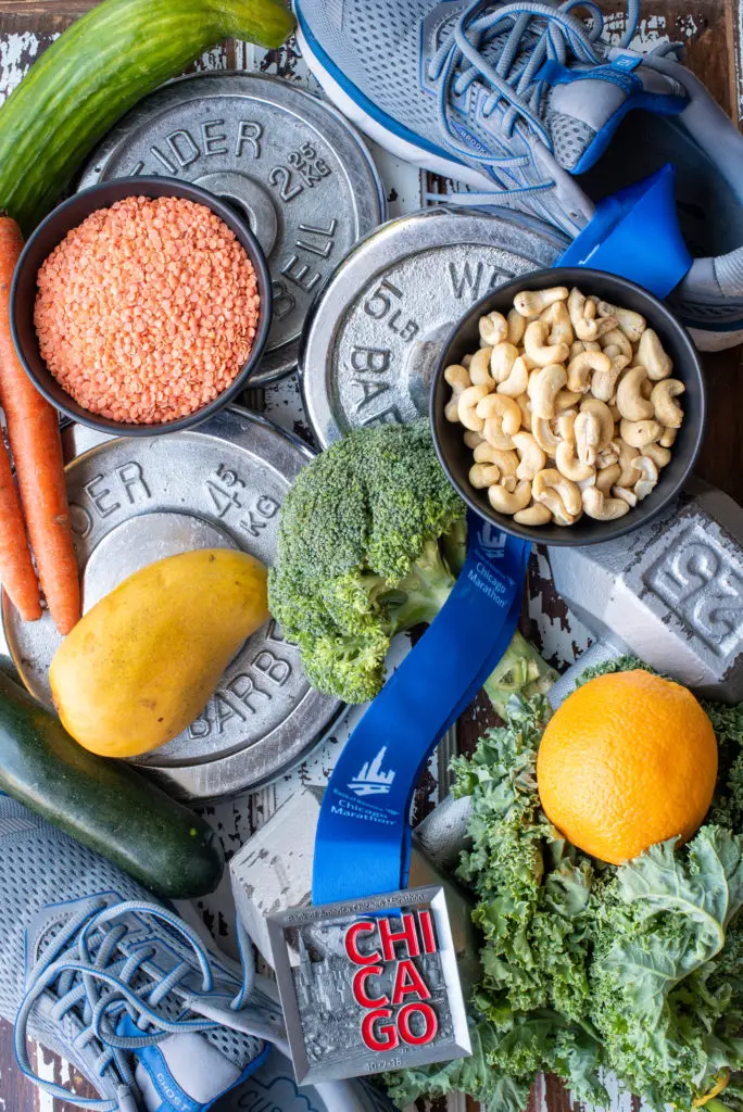 plant based athlete photo of vegetables nuts and fruit next to shoes weights and medal