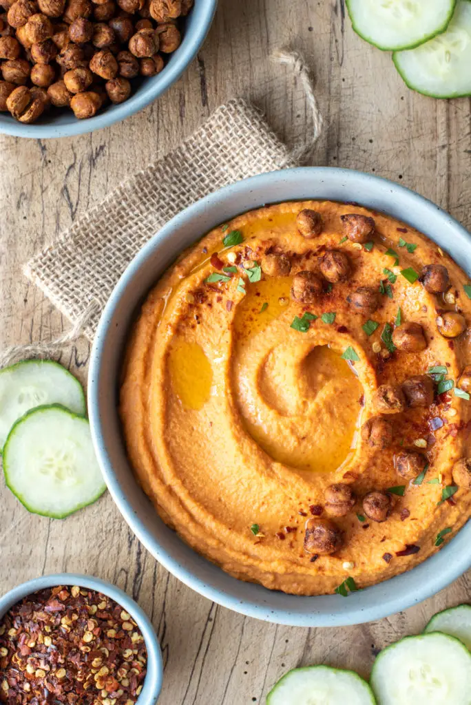 roasted red pepper hummus in bowl on cutting board