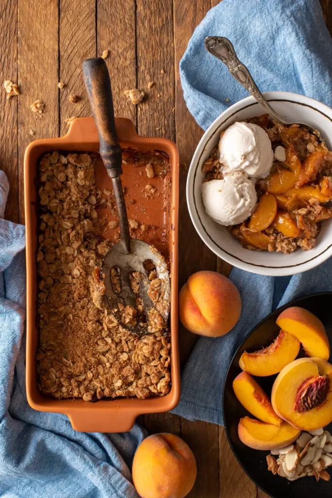 ginger peach crumble in baking dish and bowl with ice cream