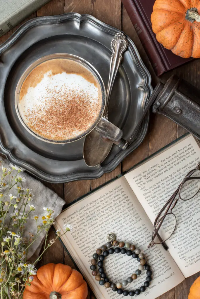 coffee in mug next to books and reading glasses