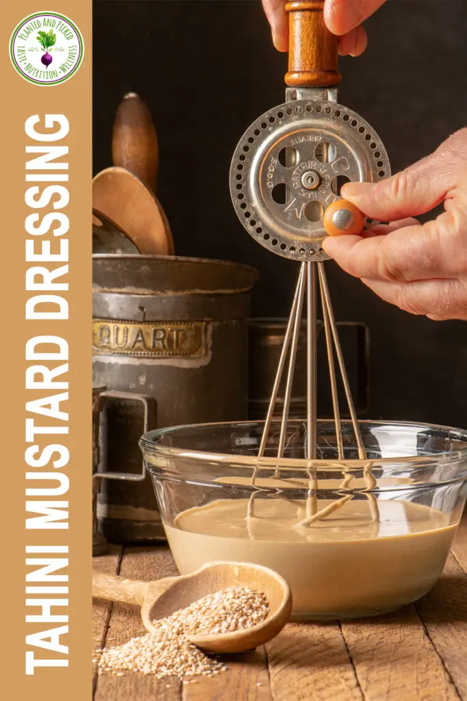 tahini mustard dressing being mixed with hand mixer in glass bowl - pinterest image