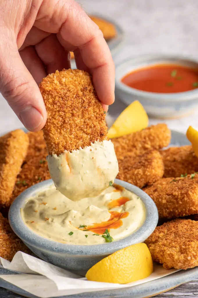 crispy tofu strip being dipped into spicy cashew avocado mayo