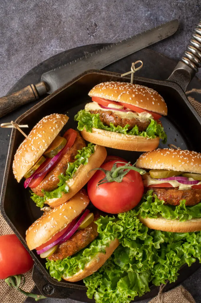 four chickpea veggie burgers arranged sideways facing in skillet