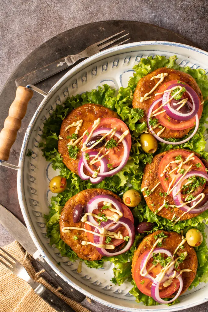 five chickpea veggie patties sitting on lettuce on serving tray
