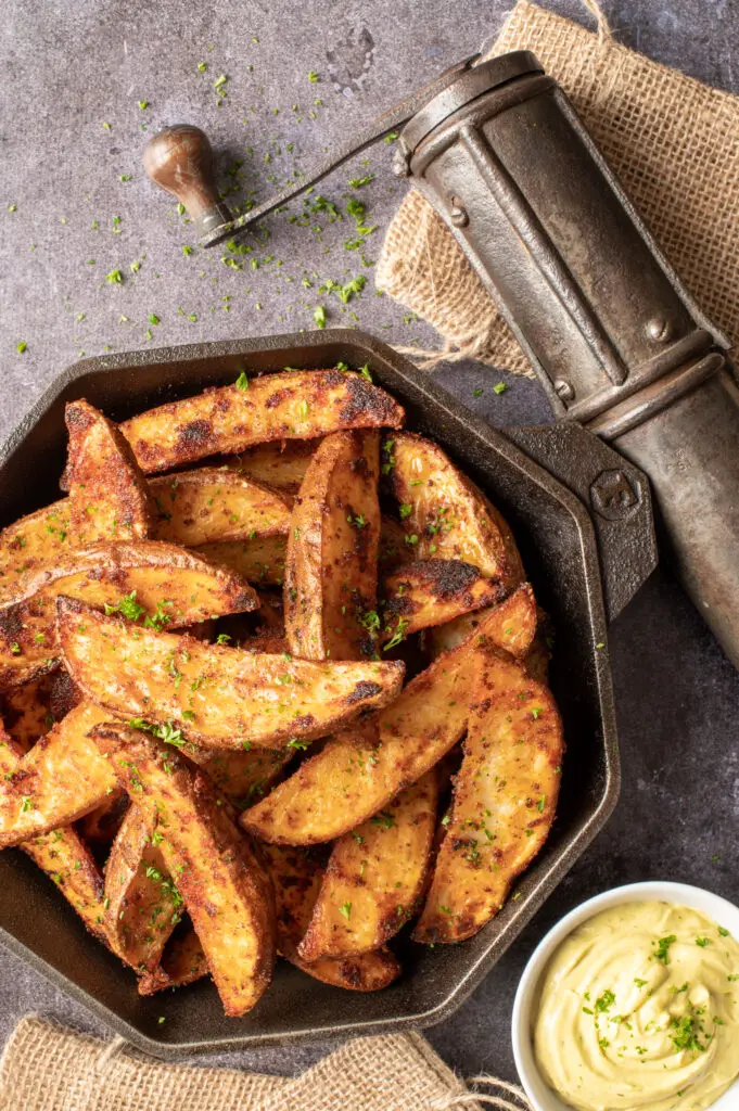 crispy oven potato wedges in skillet with small dish of avocado mayo