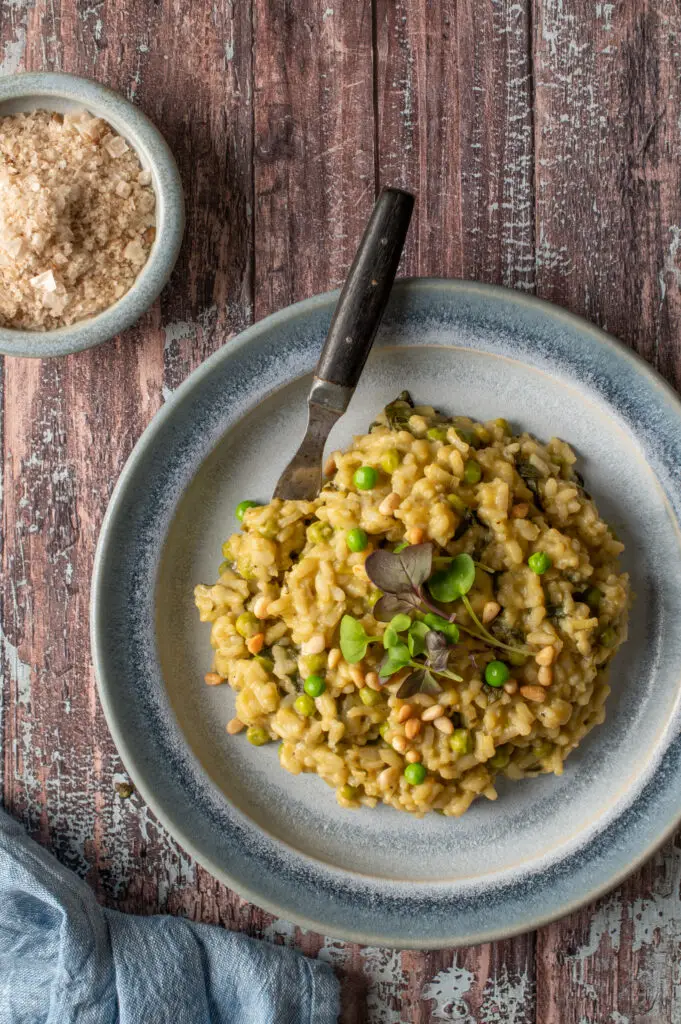 spring pesto risotto on blue pottery plate next to bowl of sea salt