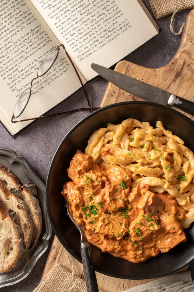 vegan hungarian tofu paprikash in black bowl on cutting board next to open book