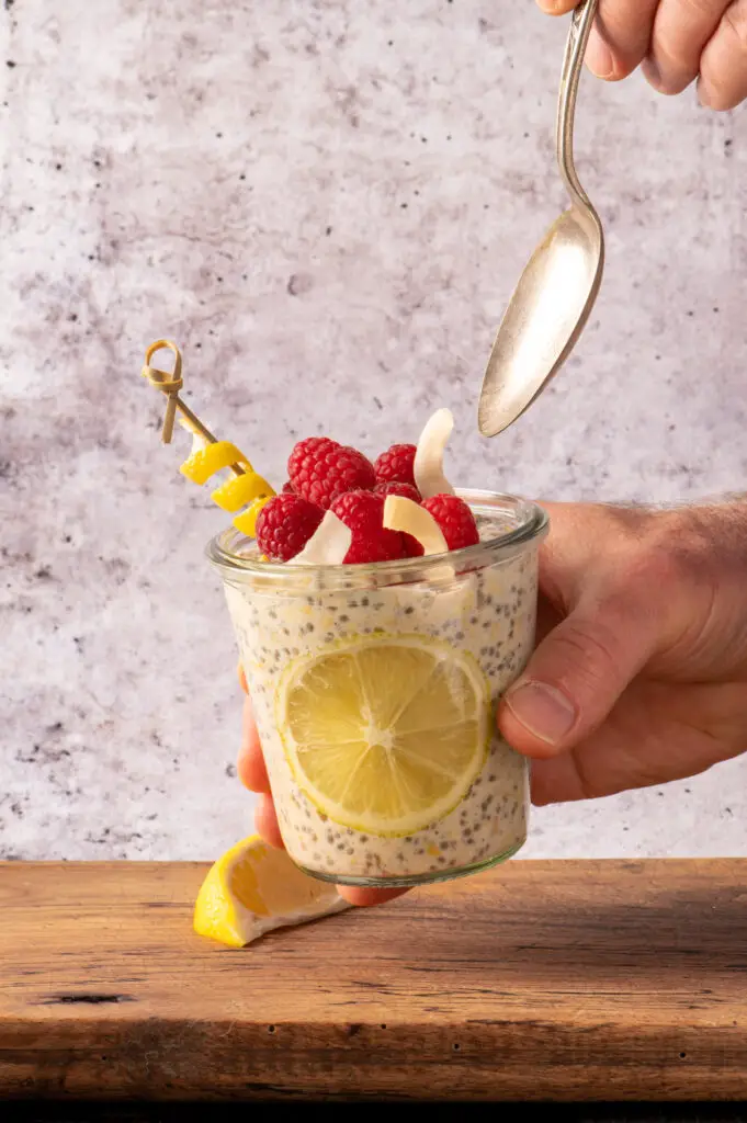 creamy lemon overnight oats in glass jar held by one hand with spoon held by other hand