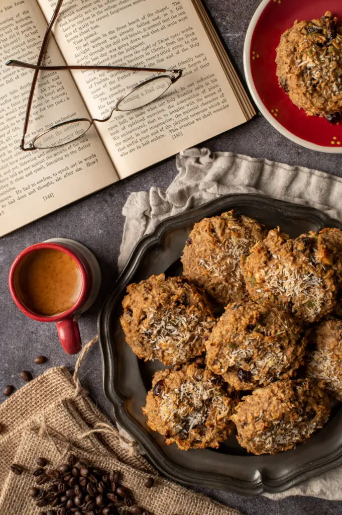 nut butter breakfast cookies on pewter plate next to open book and espresso