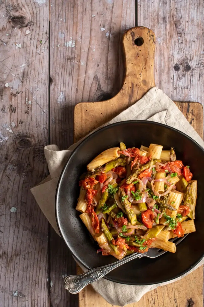 simple asparagus rigatoni in black bowl on cutting board