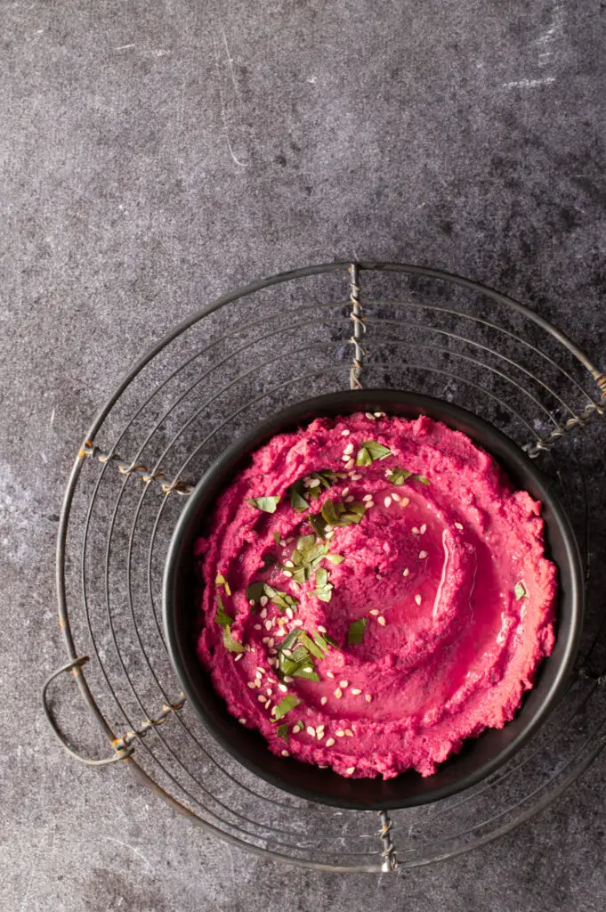 beet and dill hummus in black bowl on cooling rack