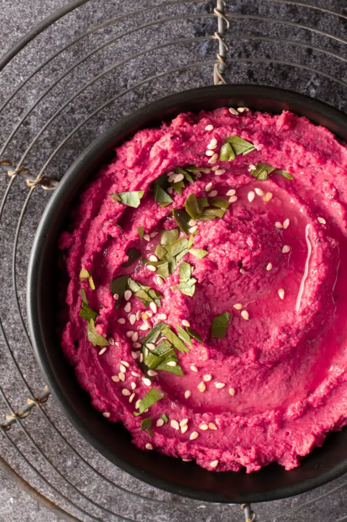 beet and dill hummus in black bowl on cooling rack