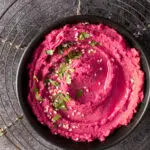 beet and dill hummus in black bowl on cooling rack - recipe image