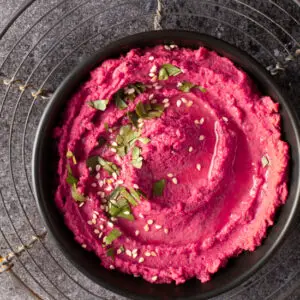 beet and dill hummus in black bowl on cooling rack - recipe image