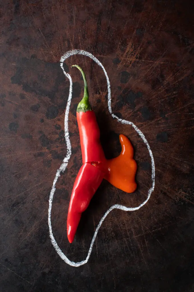 cayenne pepper hot sauce shown as if leaking from a fresh pepper