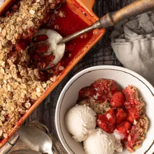 strawberry coconut crumble in bowl next to crumble in baking dish - recipe image