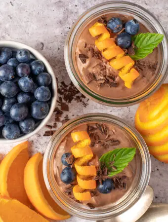 creamy chocolate coconut pudding in jars next to blueberry in dish