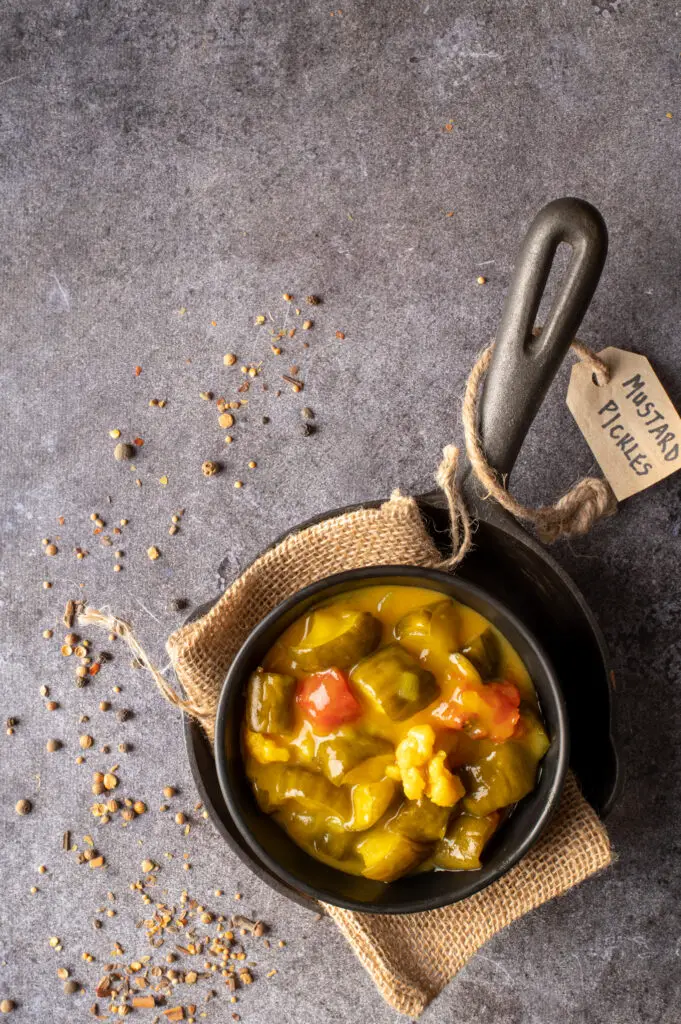 mustard pickles in black bowl sitting in small cast iron pan