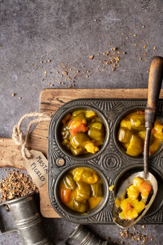 mustard pickles in muffin tin cups on cutting board