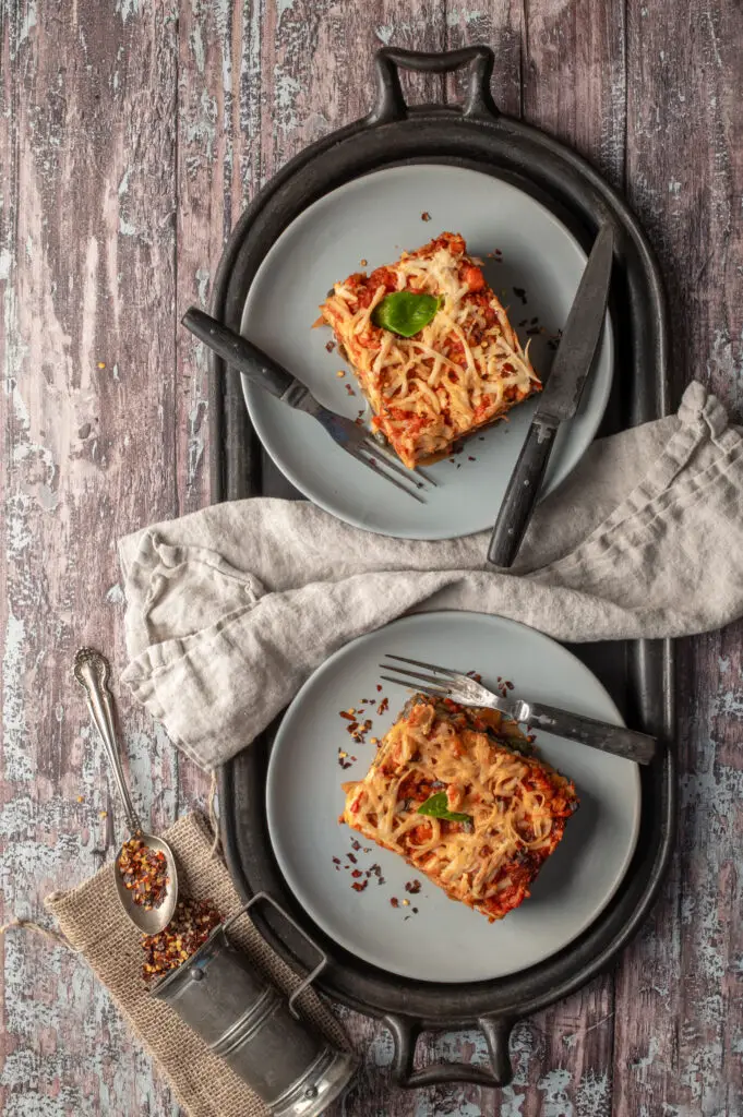 lasagne on two plates sitting on cast iron griddle