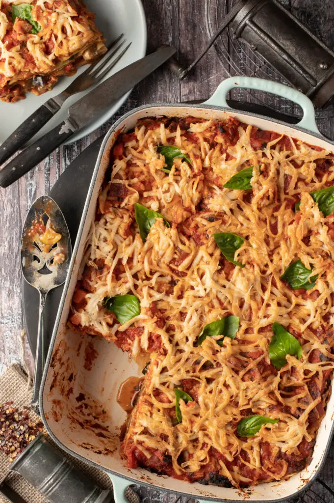 lasagne in baking dish next to lasagne on plate