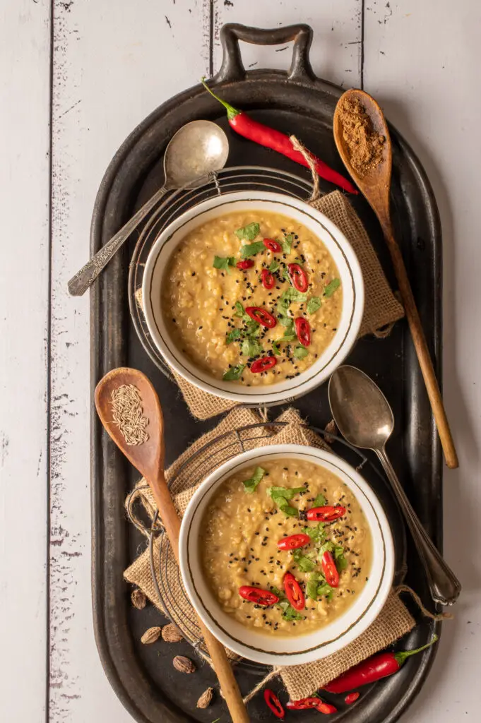 basic mung dal in two white bowls sitting on oval cast iron griddle