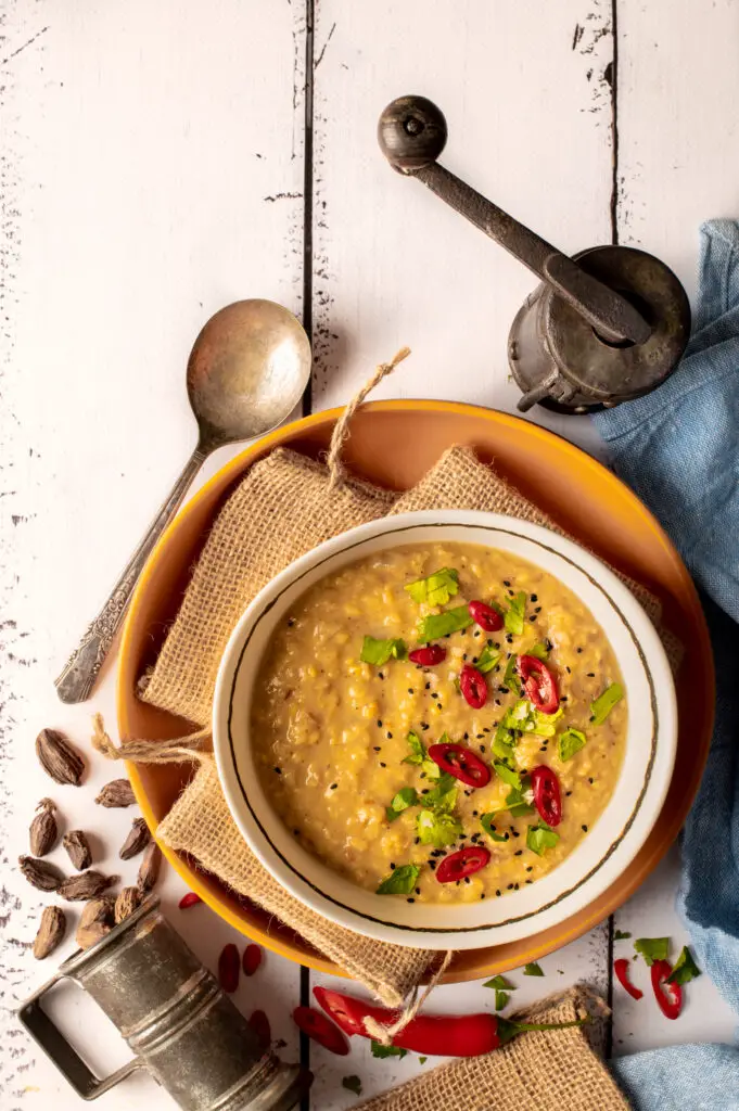 basic mung dal in white bowl next to spice mill, spoon and measuring cup