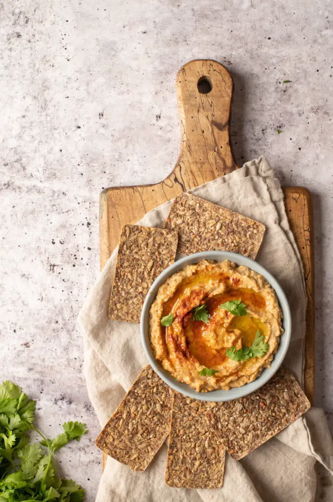 baba ganoush in bowl on cutting board with crackers