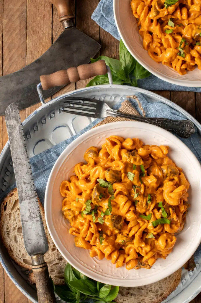 creamy roasted red pepper pasta in white bowl on tray